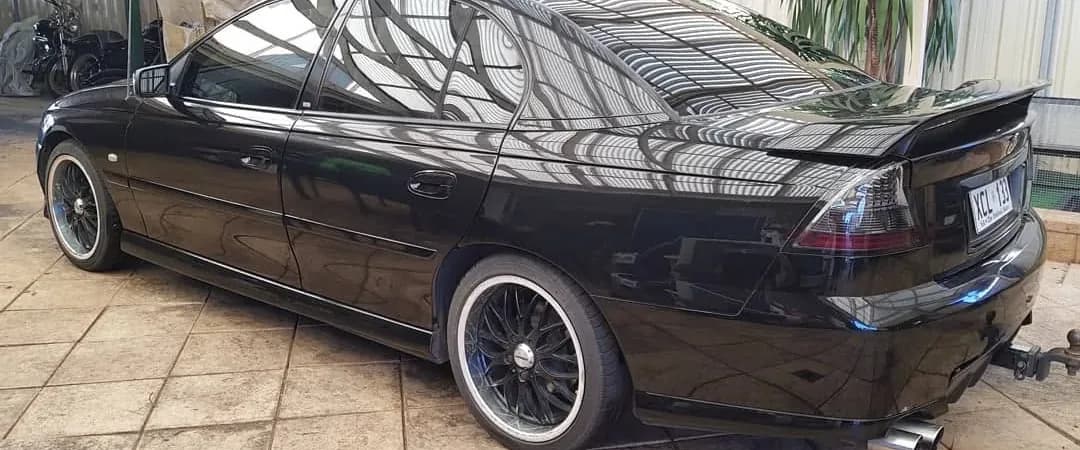 Black Holden Commodore with dark window tint parked in a driveway
